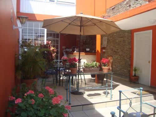 a patio with a table with an umbrella and flowers at Hotel Camba in Oaxaca City