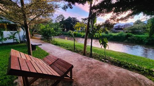 a wooden bench sitting next to a river at Canary Guesthouse in Pai