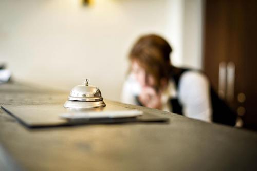 a woman sitting at a table with a bell on it at Hotel de France Wiesbaden City in Wiesbaden