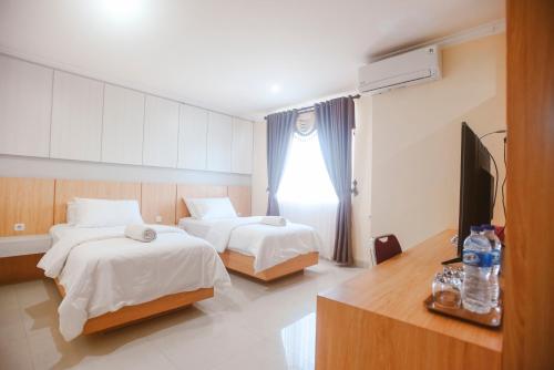 a hotel room with two beds and a television at CHRYSANT HOTEL & RESORT in Oesapa-besar