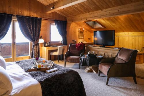 ein Hotelzimmer mit einem Bett und einem Fernseher in der Unterkunft Fer à Cheval in Megève