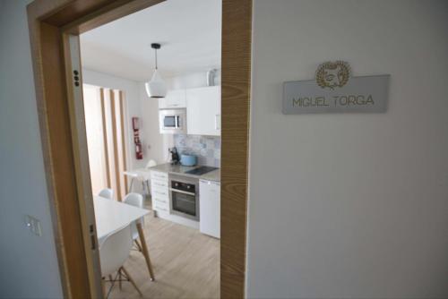 a kitchen with white cabinets and a table and a door at Camoes StudioGeral in Bragança