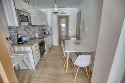 a kitchen with white cabinets and a table and chairs at Camoes StudioGeral in Bragança
