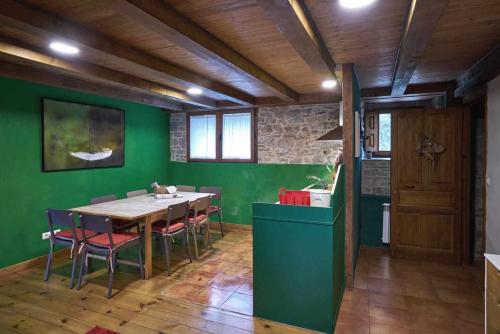 a kitchen with a table and a green wall at Casapirineos Apartamentos in Ulle
