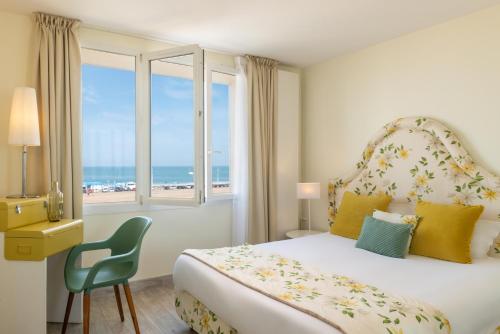 a bedroom with a bed and a window with the ocean at Hôtel de la Plage in Dieppe