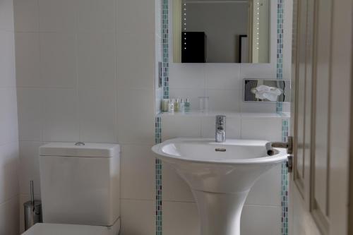 a white bathroom with a sink and a toilet at Norfolk Royale Hotel in Bournemouth