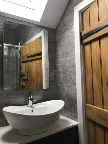 een badkamer met een witte wastafel en een spiegel bij Rustic Retreats Jacks Cottage with Hot Tub & Alpaca Walking Experiences in Matlock