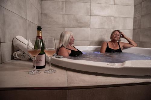 two women sitting in a bath tub with wine glasses at Hotel Faaborg Fjord in Fåborg