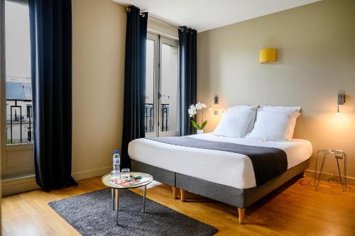a bedroom with a bed and a large window at Suites & Hôtel Helzear Champs-Elysées in Paris