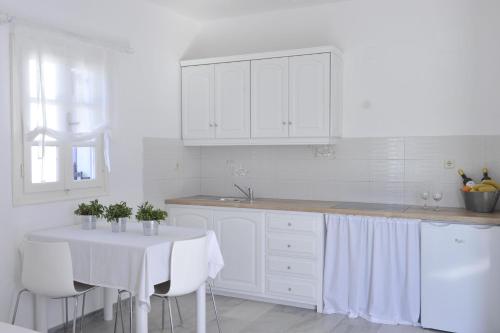a kitchen with white cabinets and a white table and chairs at Villa Irini in Naousa