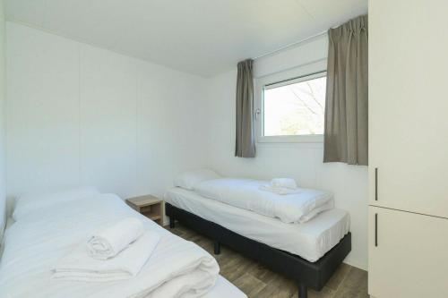 two beds in a room with a window at Chalet - Vakantiepark Hart van Zeeland in Heinkensand