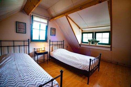 two beds in a room with two windows at Saksisch Boerderijtje in Eibergen
