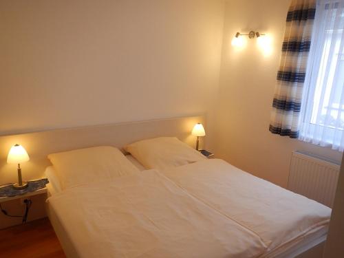 1 dormitorio con 1 cama blanca y 2 almohadas en Appartementhaus Eiergrogstube, en Helgoland