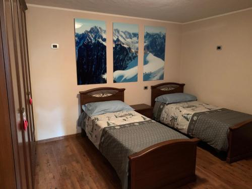two beds in a room with paintings on the wall at La Maison De Deni in Aymavilles