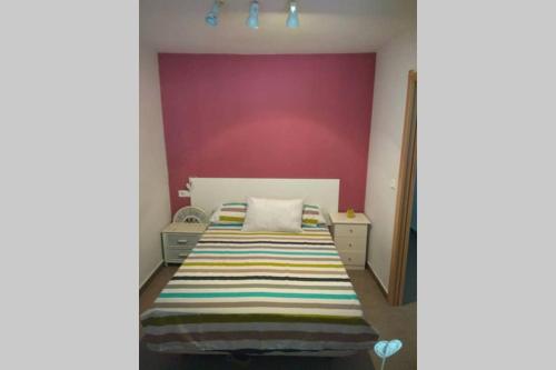 sypialnia z łóżkiem i fioletową ścianą w obiekcie APARTAMENTO RINCÓN DE LOIX ( PLAYA DE LEVANTE) w mieście Benidorm