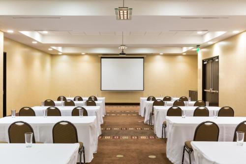 a conference room with white tables and chairs and a screen at Holiday Inn Temple - Belton by IHG in Temple