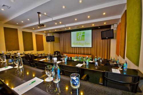 a restaurant with tables and chairs and a screen at Holiday Inn Panama Canal by IHG in Panama City