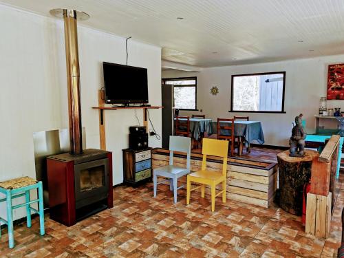 a living room with a wood stove and chairs at Cabañas & Hostal Dos Rios in Malalcahuello