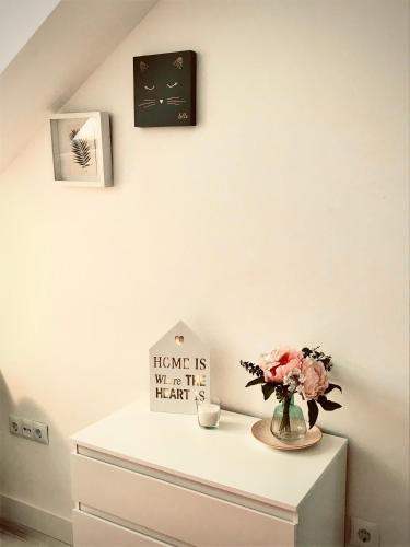 a white dresser with a vase of flowers and a clock at Confort Nordico Aranjuez garaje, NETFLIX in Aranjuez