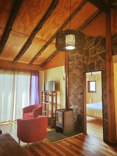 a living room with a fireplace and a bedroom at Cabañas & Hostal Dos Rios in Malalcahuello