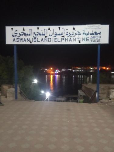a sign over a pier with a river at night at ABAZIDO Nubian Guest House in Aswan