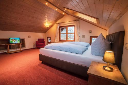 a bedroom with a large bed and a television at Hotel Garni Landhaus Traunbachhäusl in Ruhpolding