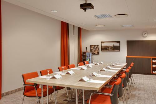a large conference room with a long table and orange chairs at Holiday Inn Berlin City East Side by IHG in Berlin