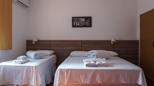 two beds in a room with towels on them at Pousada o Amanhecer in Tiradentes