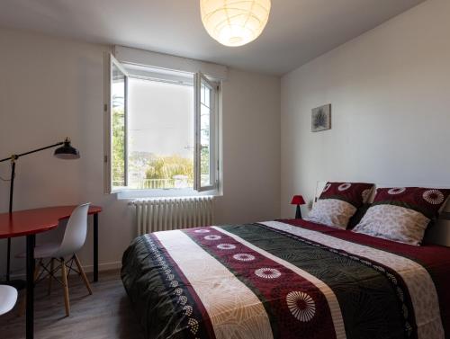 a bedroom with a bed and a table and a window at - Les Berges du Pont Valentré - in Cahors