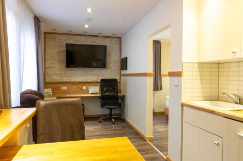 a kitchen with a desk and a television on a wall at Hotel Post mit Klimaanlage in Neckarsulm