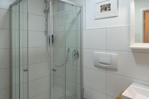 a shower in a bathroom with white tiles at Hotel Post mit Klimaanlage in Neckarsulm