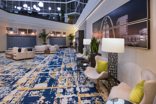 a lobby with couches and chairs on a blue rug at The Arch Convention Hotel in Saint Louis