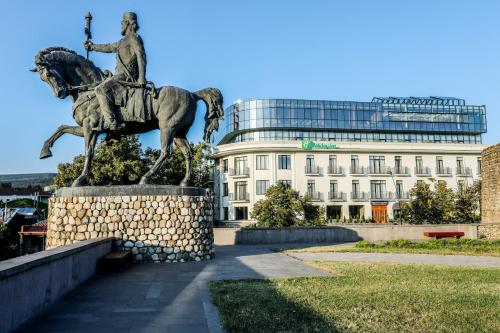 a statue of a man on a horse in front of a building at Holiday Inn Telavi by IHG in Tʼelavi