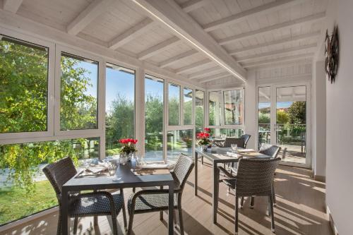 a dining room with tables and chairs and windows at Le Betulle in Colà di Lazise