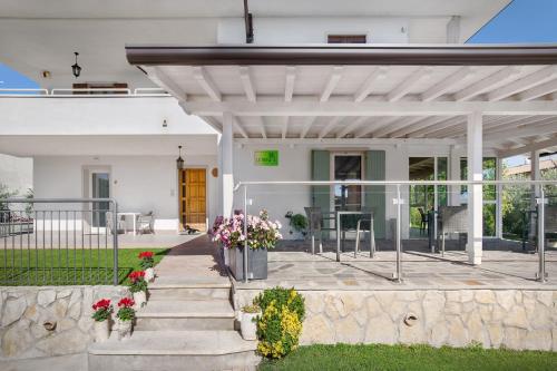 a white house with a patio with flowers at Le Betulle in Colà di Lazise
