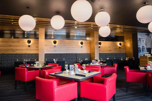 a restaurant with red chairs and tables and lights at Holiday Inn Hotel & Suites Calgary South - Conference Ctr by IHG in Calgary
