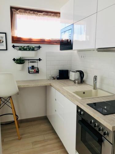 a kitchen with white cabinets and a counter top at Belvárosi Stúdió Apartman in Kecskemét