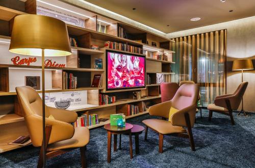 a library with chairs and a tv and bookshelves at Holiday Inn - Villingen - Schwenningen, an IHG Hotel in Villingen-Schwenningen