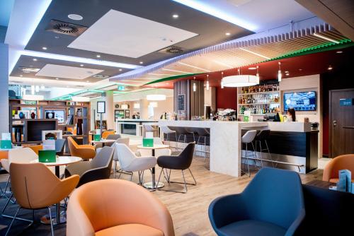 a restaurant with tables and chairs and a bar at Holiday Inn Dąbrowa Górnicza-Katowice by IHG in Dąbrowa Górnicza