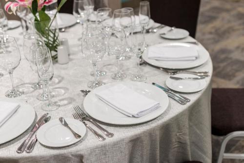 a table with white plates and wine glasses on it at Holiday Inn - Lima Airport by IHG in Lima