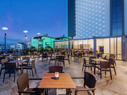 a restaurant with tables and chairs and a building at Holiday Inn Antalya - Lara by IHG in Antalya