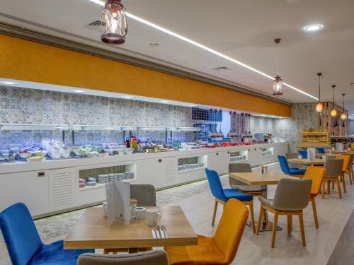 a restaurant with wooden tables and blue chairs at Holiday Inn Antalya - Lara by IHG in Antalya