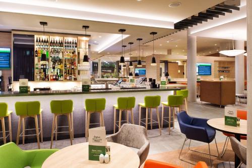 a bar in a restaurant with green chairs and tables at Holiday Inn Frankfurt Airport by IHG in Frankfurt/Main