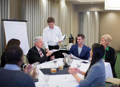 a group of people sitting around a table in a meeting at Holiday Inn - Long Island - ISLIP Arpt East by IHG in Holtsville