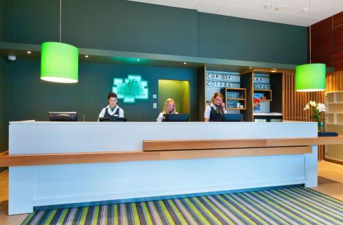 a lobby with three people sitting at a reception counter at Holiday Inn Tampere - Central Station by IHG in Tampere