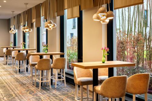 a row of tables and chairs in a room with windows at Holiday Inn Düsseldorf City – Toulouser Allee by IHG in Düsseldorf