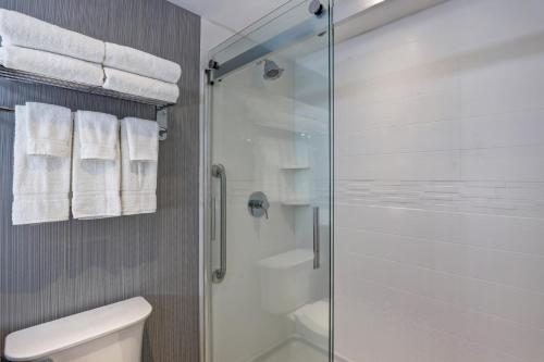 a bathroom with a glass shower with a toilet and towels at Holiday Inn - Mississauga Toronto West by IHG in Mississauga