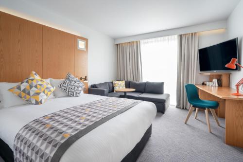 a hotel room with a large bed and a desk at Holiday Inn Bournemouth by IHG in Bournemouth