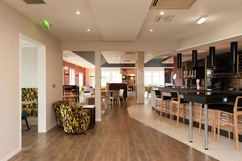 ein Esszimmer und eine Küche mit einer Bar und Stühlen in der Unterkunft Holiday Inn Darlington - NORTH A1M, JCT.59 by IHG in Darlington