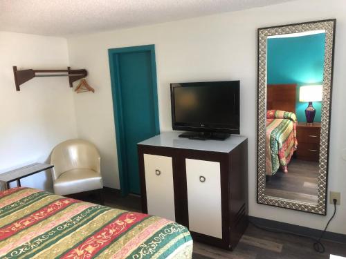 Habitación de hotel con TV y espejo. en Econo Lodge, en Georgetown